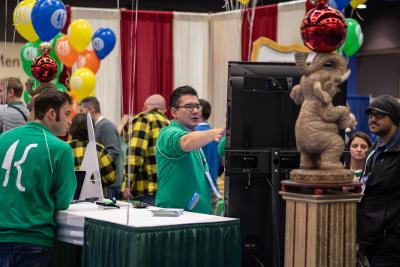 People in circus-themed trade booth with man pointing at screen
