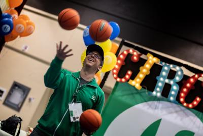 Employee in a company jacket juggling mini basketballs